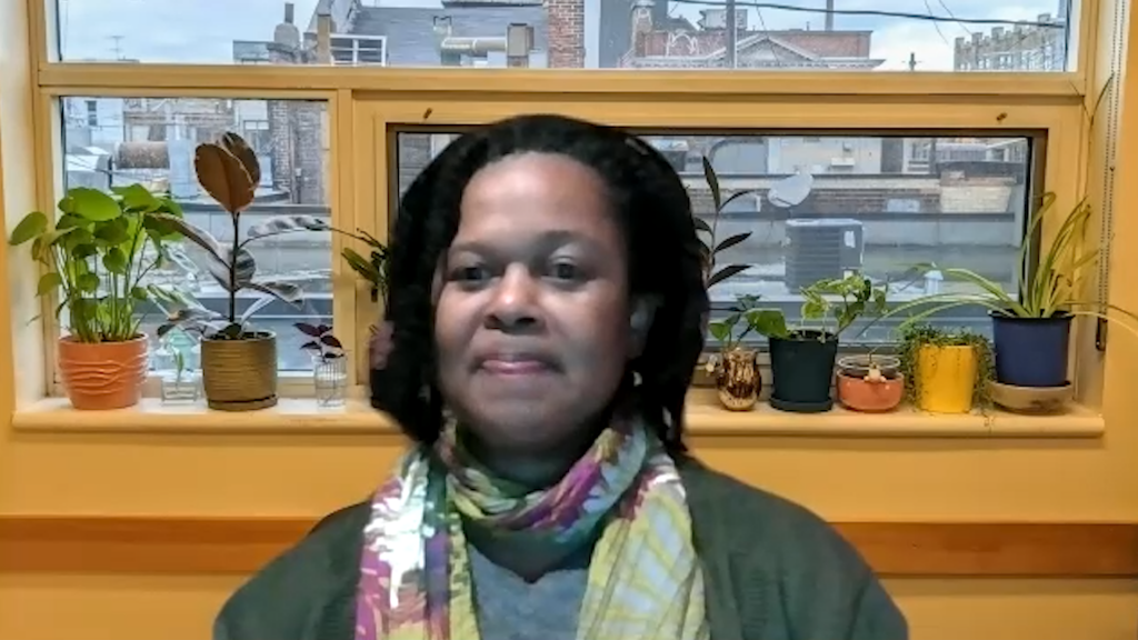 Penelope, our case study patient, smiles from her apartment over Zoom. Houseplants line the window behind her.
