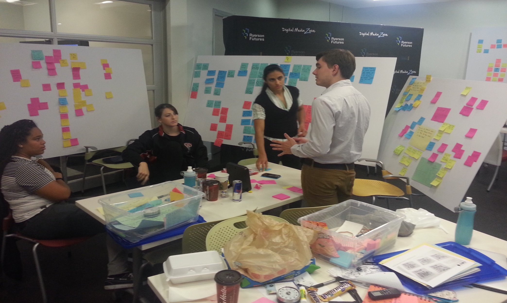Students in design thinking course surrounded by poster boards filled with sticky notes.