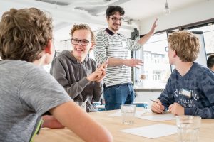 Two students listening to two other students who are explaining ideas for a group assignment.