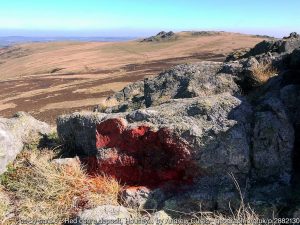 A rock outcropping with a deep red hue overlooking a large savannah.