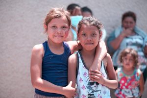Two young girls in San Diego. They have their arms around each other and are looking at the camera.