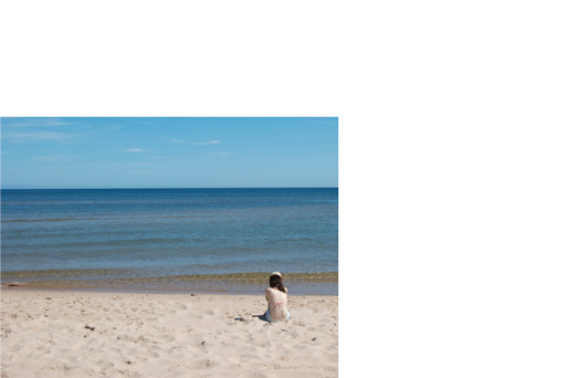 Photography of a beach with someone sitting by the ocean in the right side of the picture