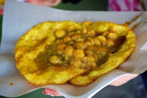 Trinidad doubles is the most iconic street food of Trinidad and Tobago. It consists of two soft, turmeric-flavoured flatbreads called bara, which are filled with a fragrant curried chickpea stew (channa) and topped with an array of sweet, spicy, and tangy chutney. Click the image to learn more about its history and origins at cookingwithria.com