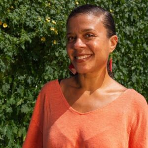 This is an image of Nicole Austin, a food justice advocate and environmentalist. She is standing in front of lush greenery of the urban rooftop at TMU, reflecting her vibrant commitment to community-based food sovereignty and environmental justice.