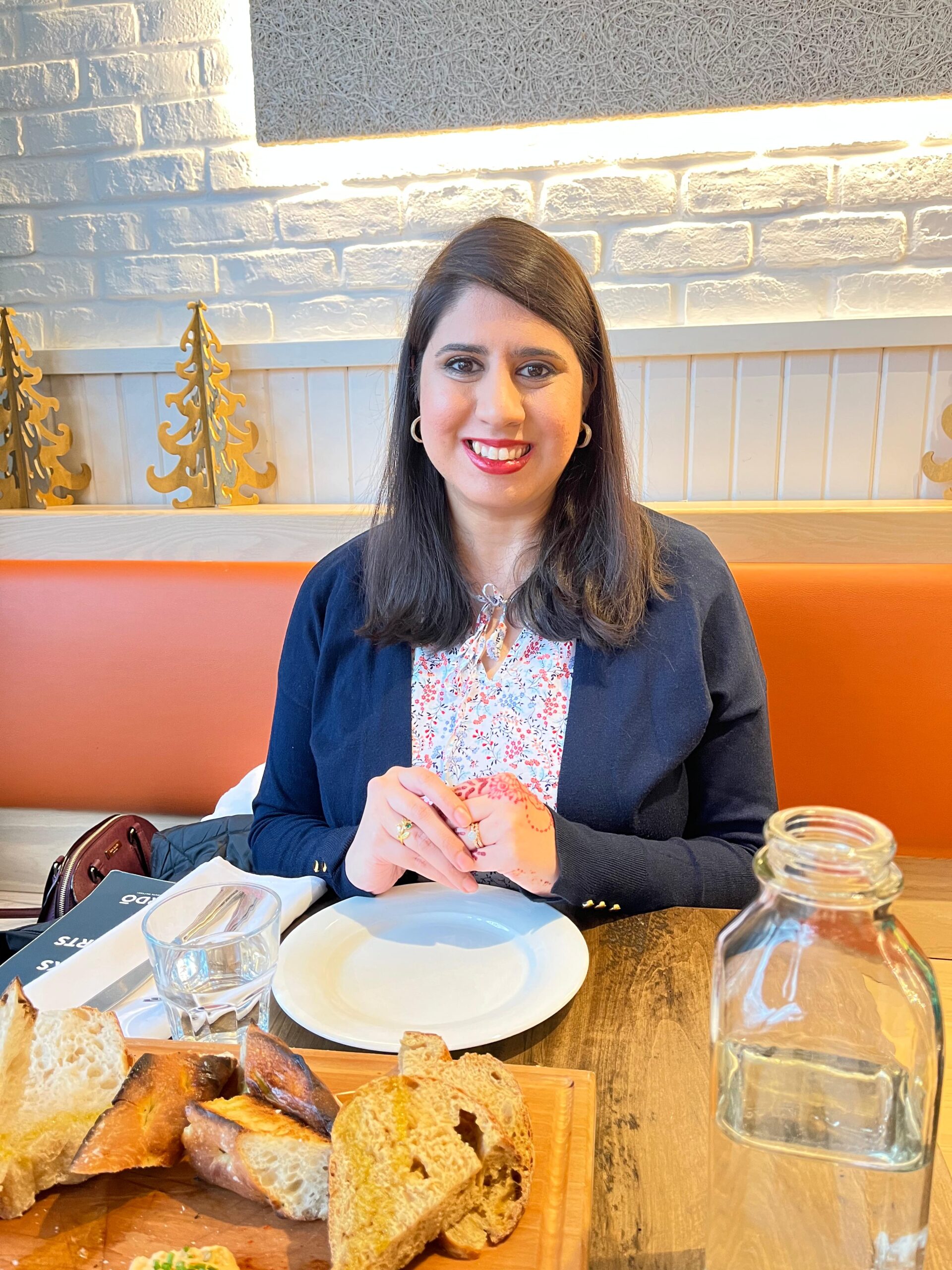 Headshot of Sherana, smiling while seated at a farm-to-table restaurant. The setting reflects her passion for food and inclusive nutrition—key themes in her work on the Anti-Black Racism in Dietetics project.