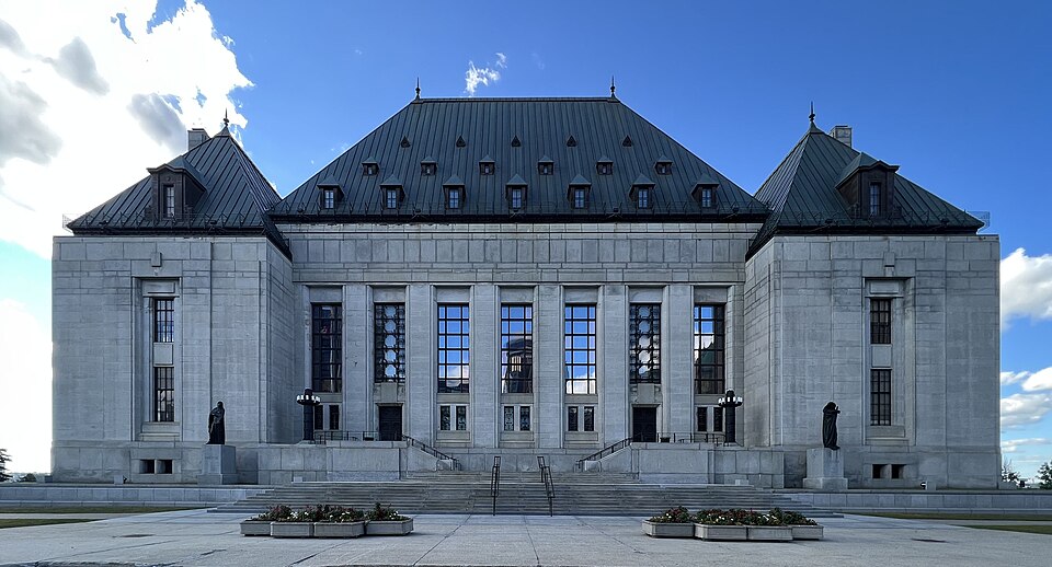 Front facade of the Supreme Court of Canada, a symmetrical grey stone building with a steep roof and tall windows, photographed in 2022.