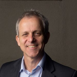 A photo of Michael Bach, a white man with grey hair and brown eyes. He is smiling.