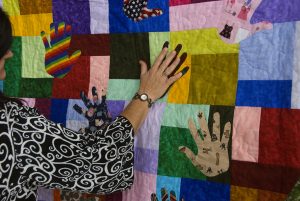 Image of quilt made up of different coloured fabrics and handprints.