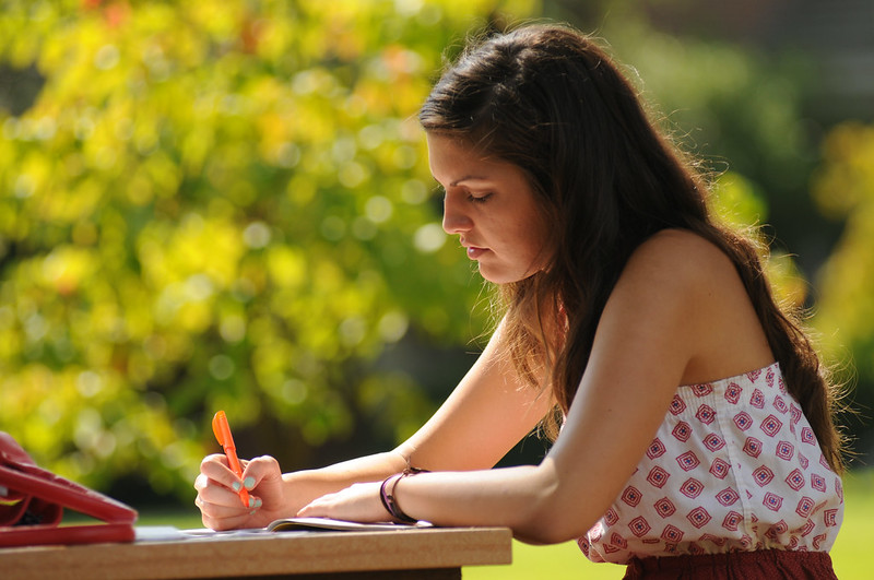 Person outside highlighting a book outside.