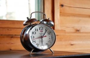 An alarm clock sitting on a wooden table.