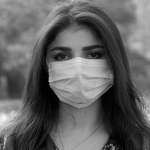 a woman with long hair in a surgical mask