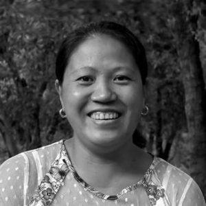 A woman with a broad smile with earrings and dark hair.